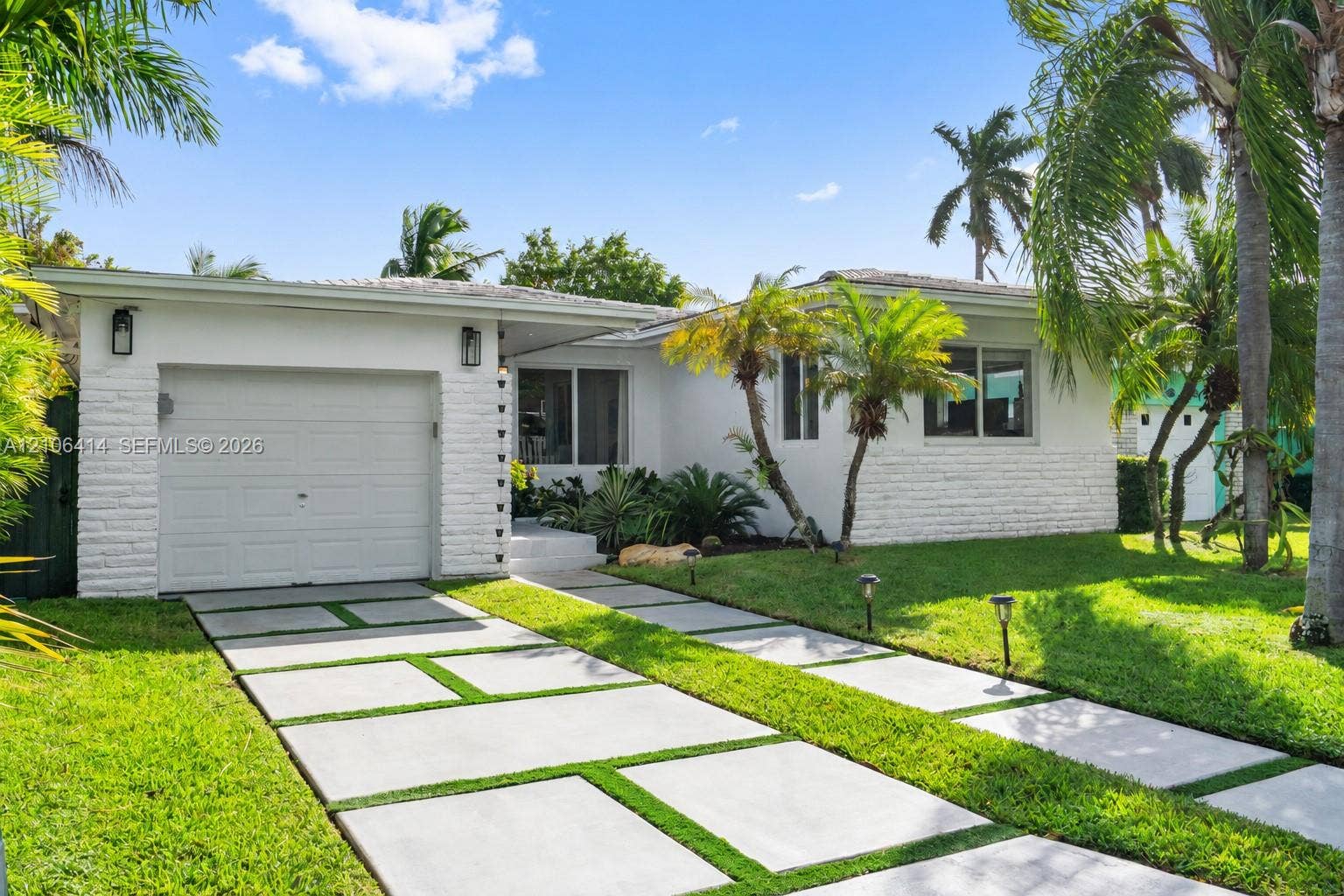 9133 Garland Avenue, Surfside, FL 33154 Exterior featuring a white painted brick facade, single-car garage, and a geometric concrete paver driveway with integrated turf