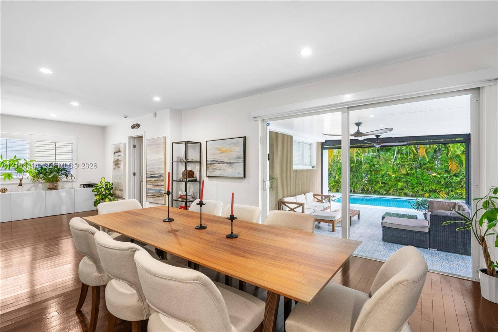 9133 Garland Avenue, Surfside, FL 33154 Open-concept dining area featuring wood-finish flooring, recessed lighting, white built-in cabinetry, and large sliding glass doors providing access to a covered patio and swimming pool