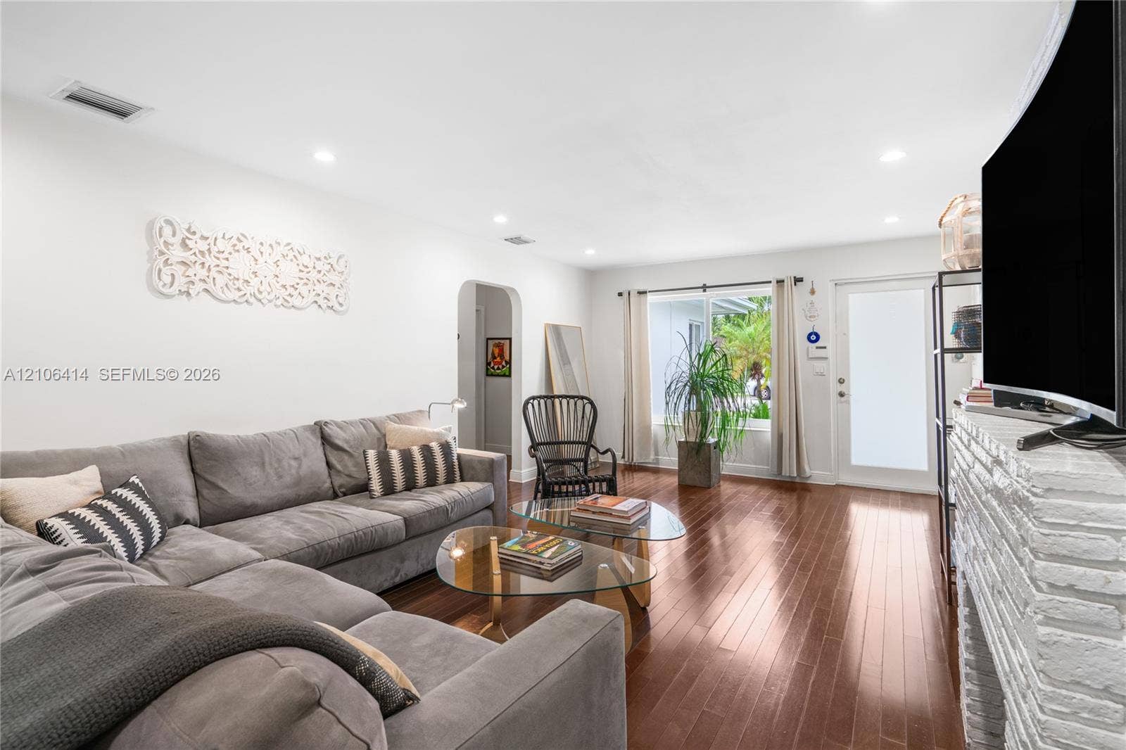 9133 Garland Avenue, Surfside, FL 33154 Living area featuring wood-finish flooring, white-painted brick fireplace, recessed lighting, arched entryway, and a glass-panel entry door