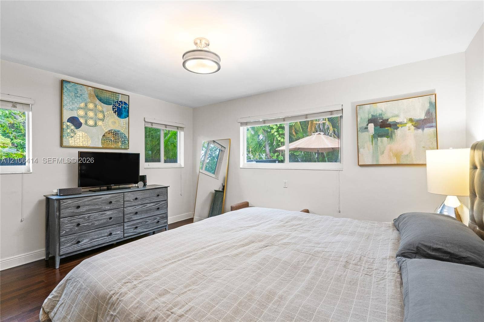 9133 Garland Avenue, Surfside, FL 33154 Bedroom interior featuring dark wood-finish flooring, multi-pane windows, and a circular drum flush-mount light fixture