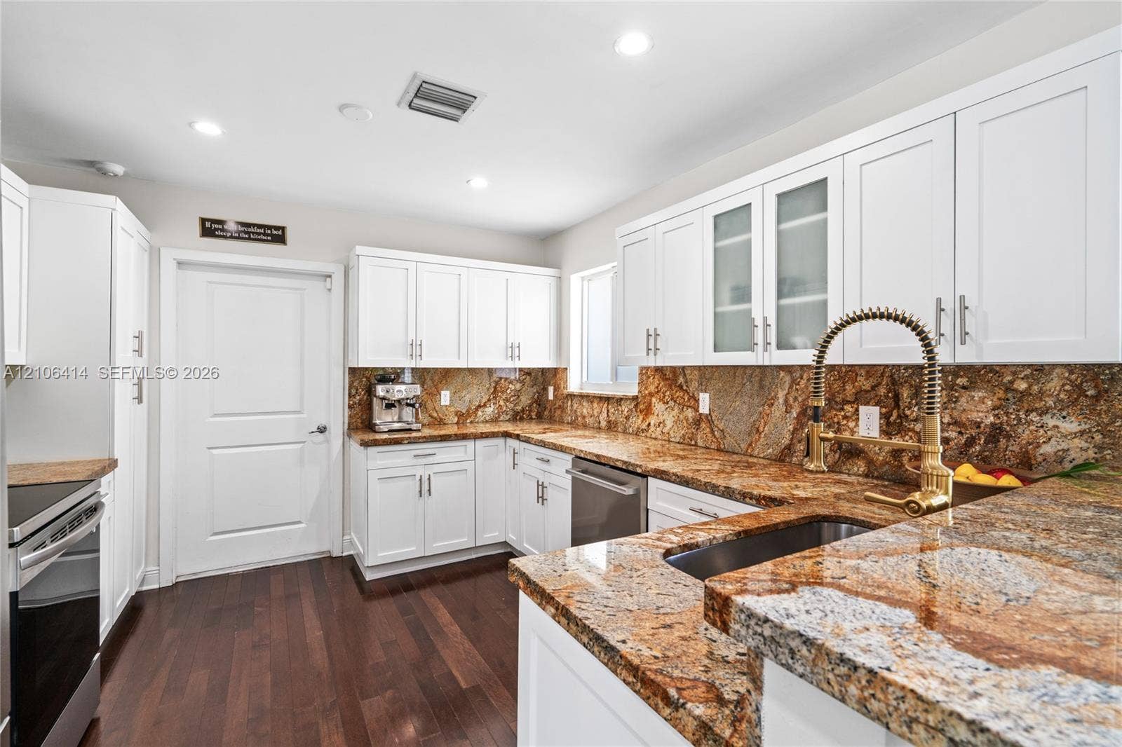 9133 Garland Avenue, Surfside, FL 33154 Kitchen featuring white shaker-style cabinetry, natural stone countertops with integrated backsplash, wood-finish flooring, undermount sink with high-arc pull-down faucet, and stainless steel appliances