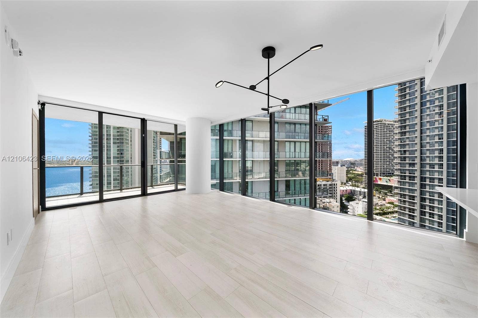 Floor-to-ceiling glass windows, wood-finish flooring, modern geometric chandelier, and open-plan layout