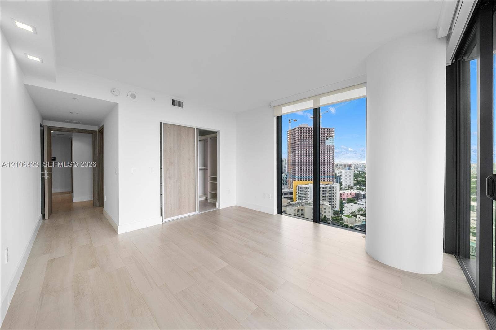 Floor-to-ceiling windows, wood-finish flooring, recessed lighting, and built-in closet with sliding doors