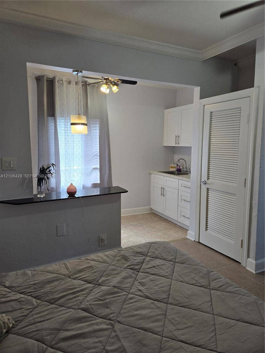 5712 Hollywood Boulevard, #3, Hollywood, Hollywood, FL 33021 Kitchenette featuring white shaker-style cabinetry, solid-surface countertop with bar-style overhang, undermount sink, and louvered-panel door