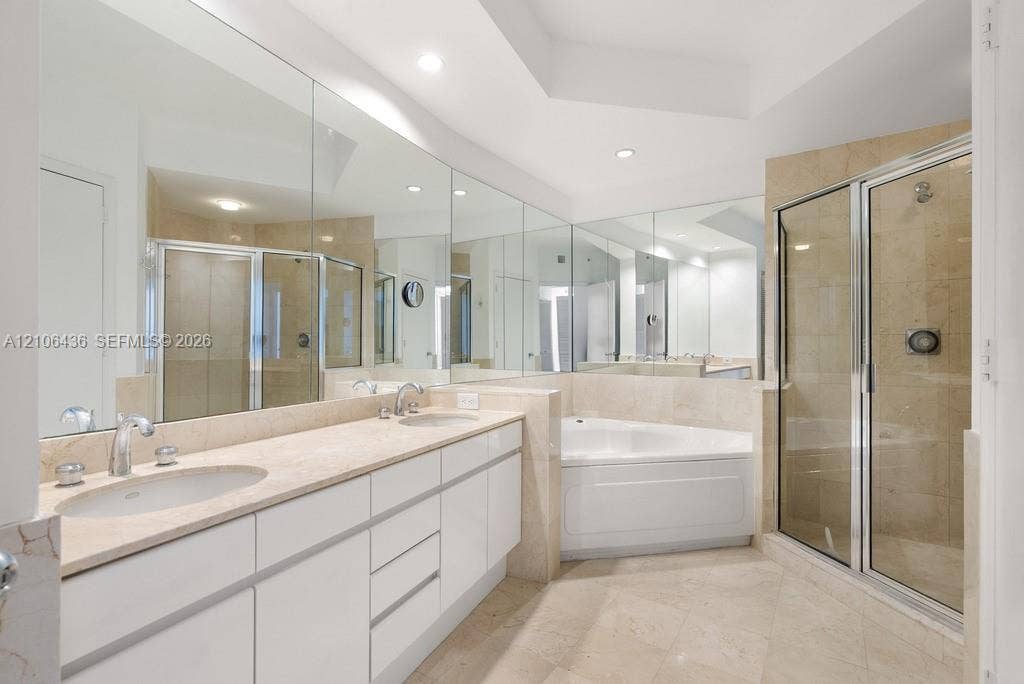 808 Brickell Key Drive, #2102, Miami, Miami, FL 33131 Double vanity with light-toned stone countertop, expansive wall-to-wall mirrors, recessed lighting, corner soaking tub, and enclosed shower with stone-tile surround