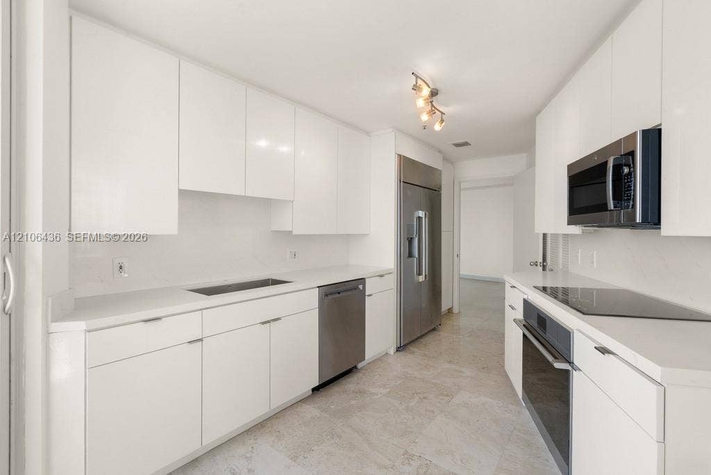 808 Brickell Key Drive, #2102, Miami, Miami, FL 33131 Kitchen featuring flat-panel white cabinetry, stone-surface countertops, full-suite stainless steel appliances, and stone tile flooring