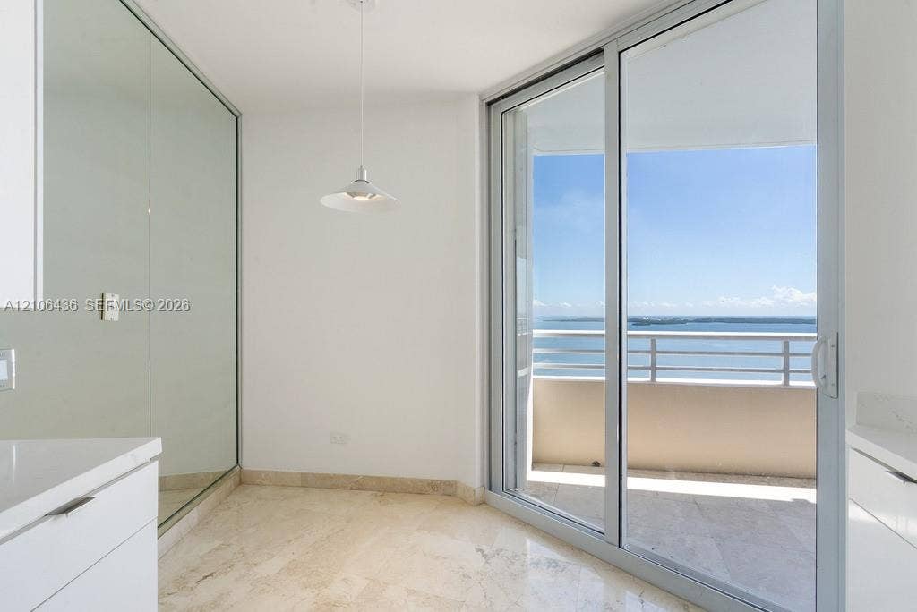 808 Brickell Key Drive, #2102, Miami, Miami, FL 33131 Floor-to-ceiling mirror paneling, stone flooring, minimalist pendant lighting, and full-height sliding glass doors opening to a balcony with water exposure