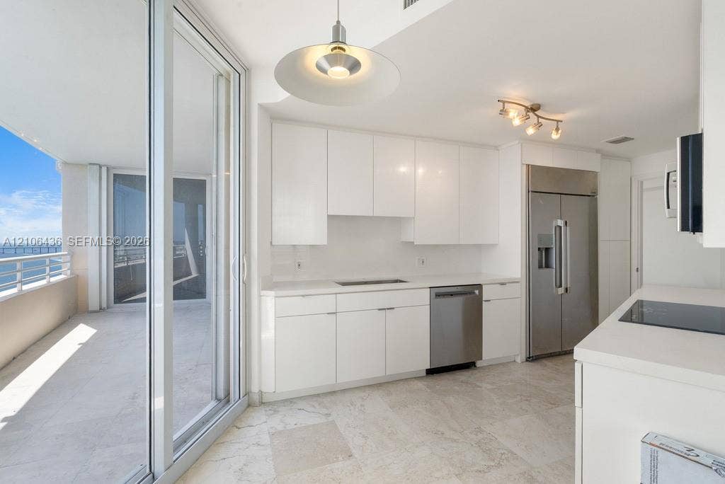 808 Brickell Key Drive, #2102, Miami, Miami, FL 33131 Kitchen featuring flat-panel white cabinetry, stone flooring, stainless steel appliances, and sliding glass doors opening to a balcony