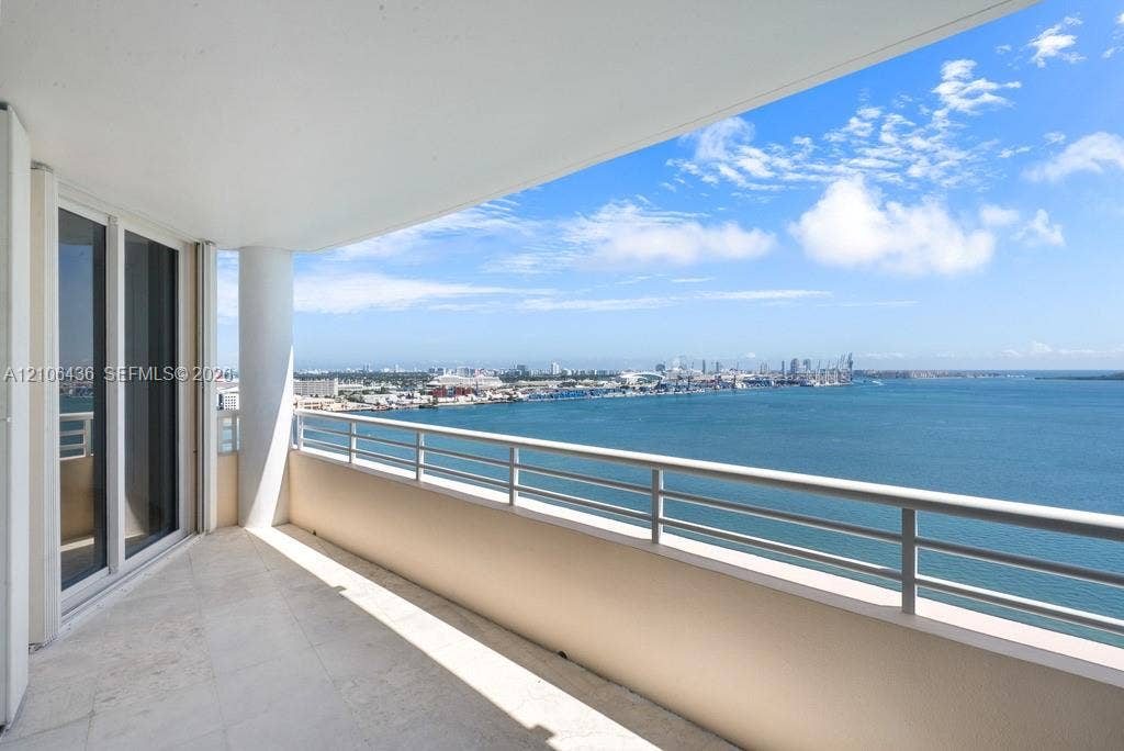 808 Brickell Key Drive, #2102, Miami, Miami, FL 33131 Covered balcony featuring stone-finish flooring, a sleek metal railing, a structural support column, and floor-to-ceiling glass sliding doors