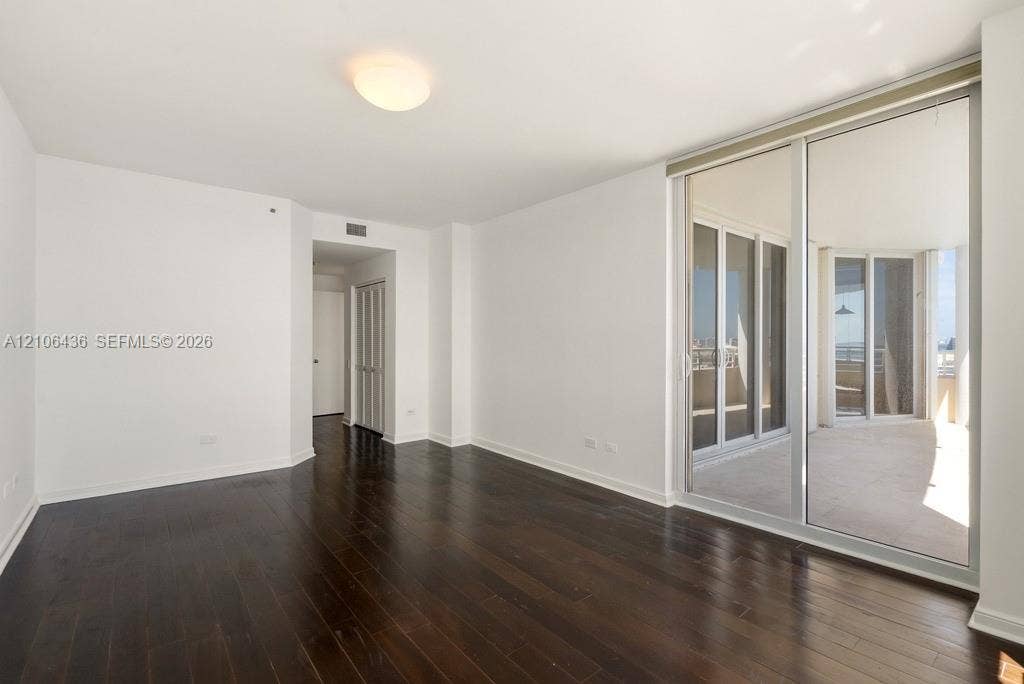 808 Brickell Key Drive, #2102, Miami, Miami, FL 33131 Interior space featuring dark wood-finish flooring, floor-to-ceiling glass sliding doors, and a private balcony with exterior railings