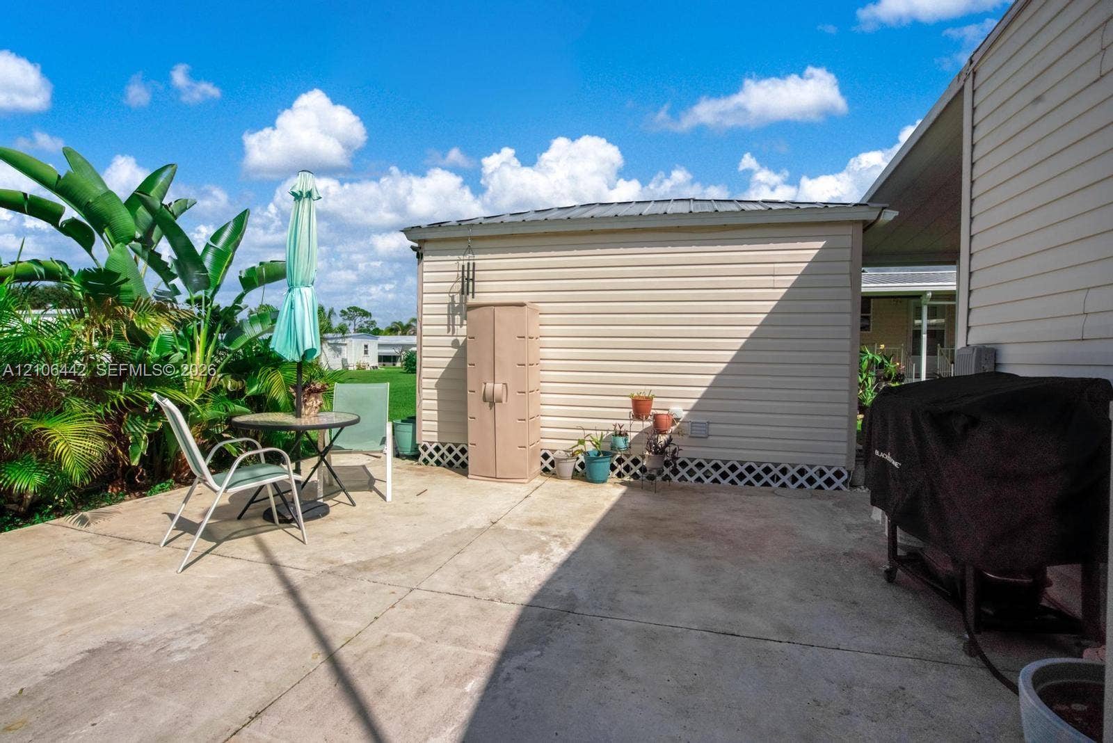 Concrete patio featuring light-colored vinyl siding, a metal roof, and lattice skirting