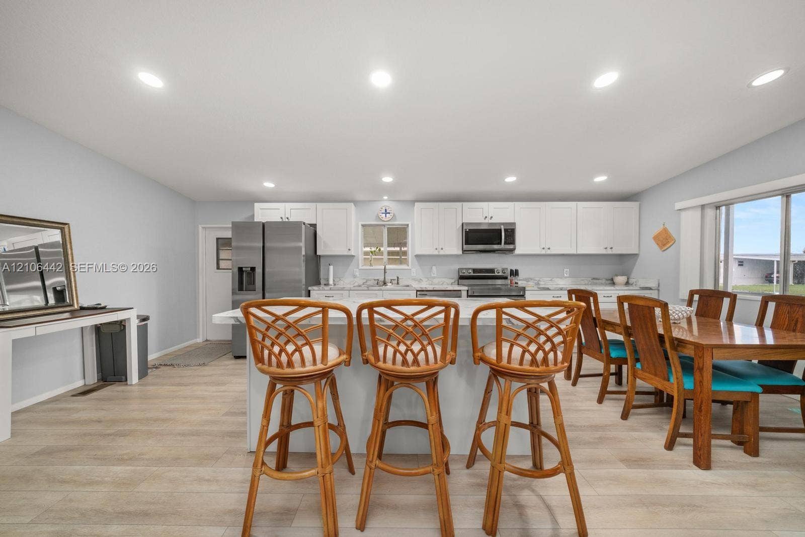 Kitchen featuring white cabinetry, stone-finish countertops, stainless steel appliances, a center island, and wood-finish flooring
