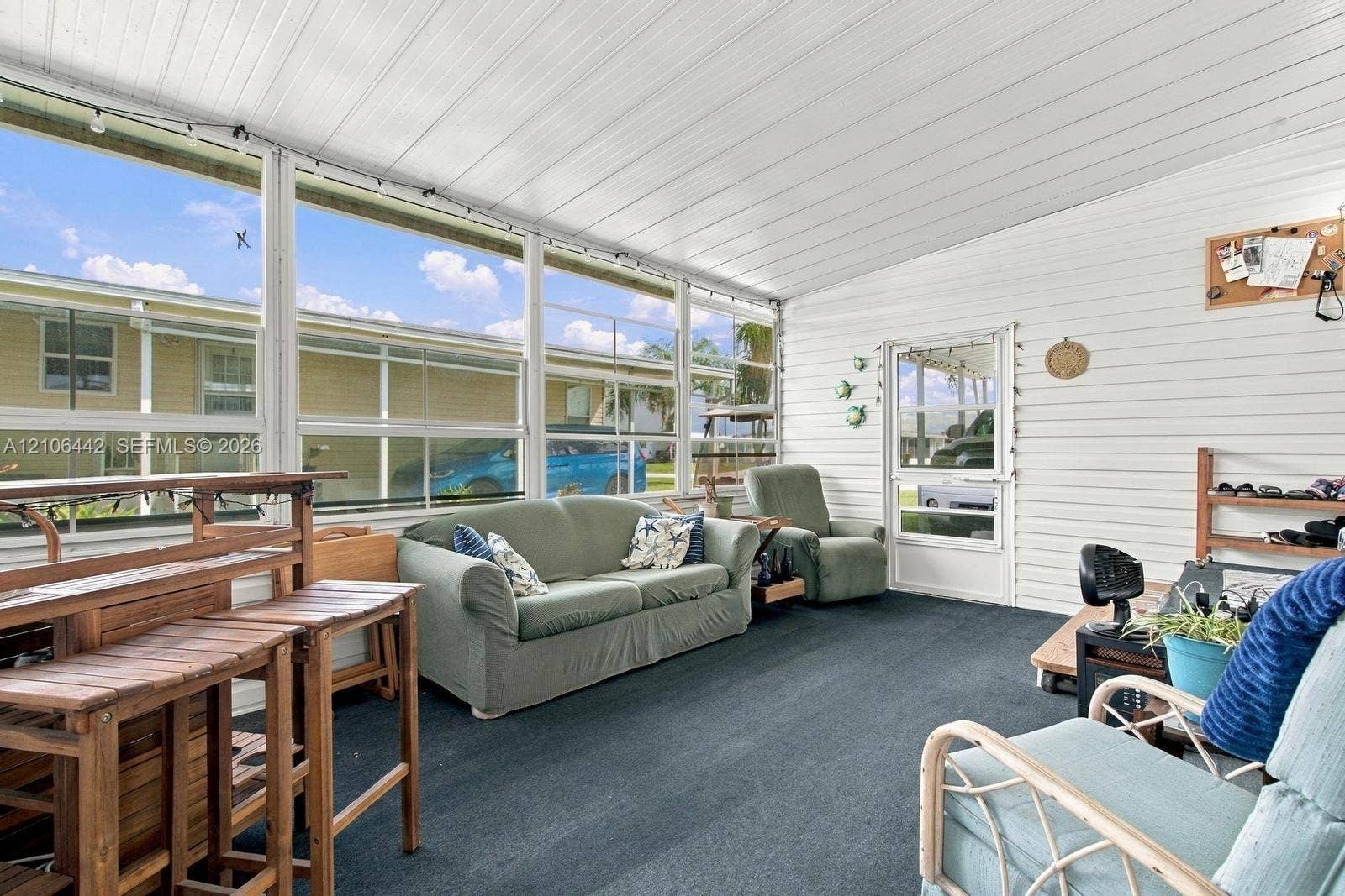 Enclosed patio featuring floor-to-ceiling screen panels, white horizontal siding, white beadboard-style ceiling, and a full-height glass entry door