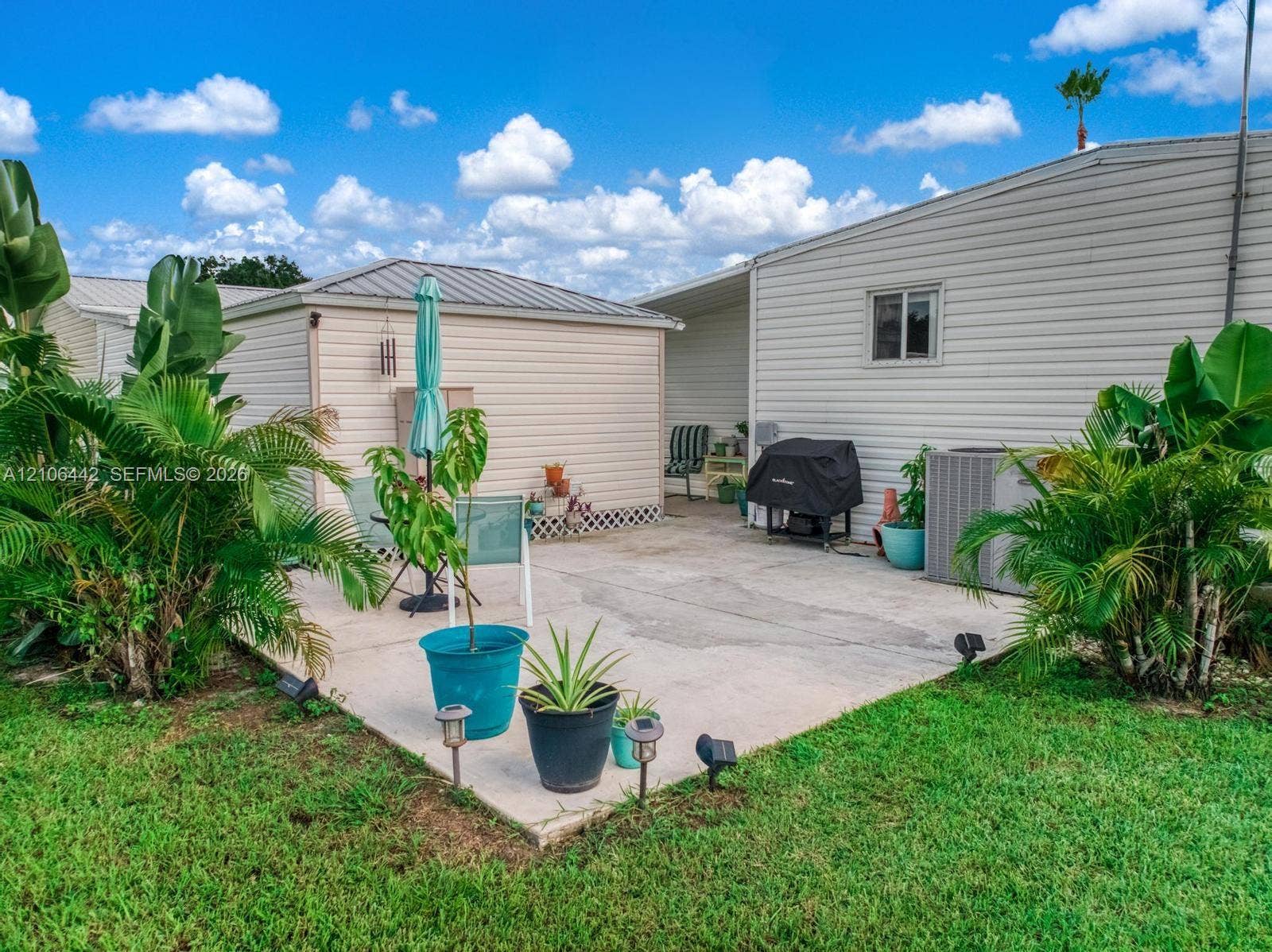 Concrete patio featuring a detached storage structure, exterior siding, and low-voltage path lighting