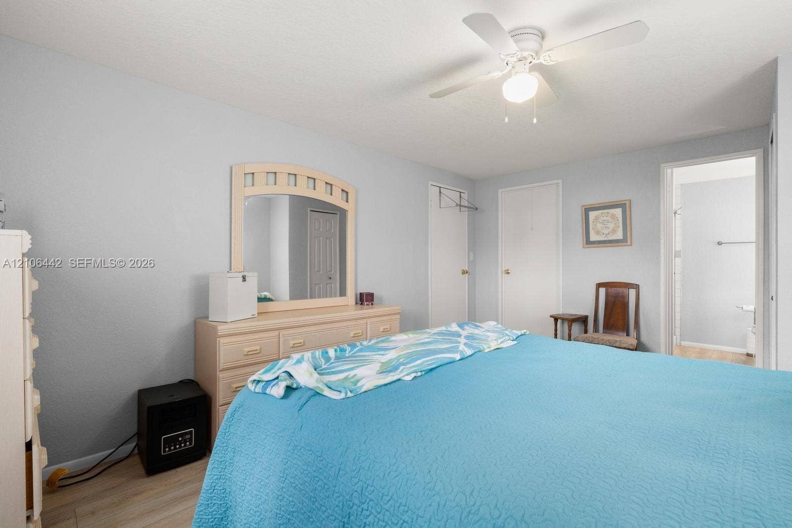 Bedroom featuring wood-finish flooring, a white ceiling fan with integrated lighting, and multiple interior doors