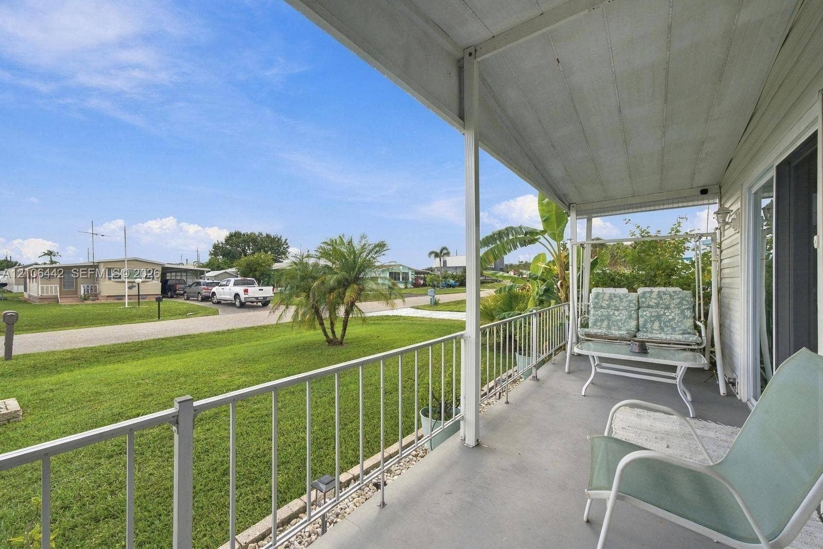 Covered exterior porch featuring a painted concrete surface, metal railings, and a slatted ceiling