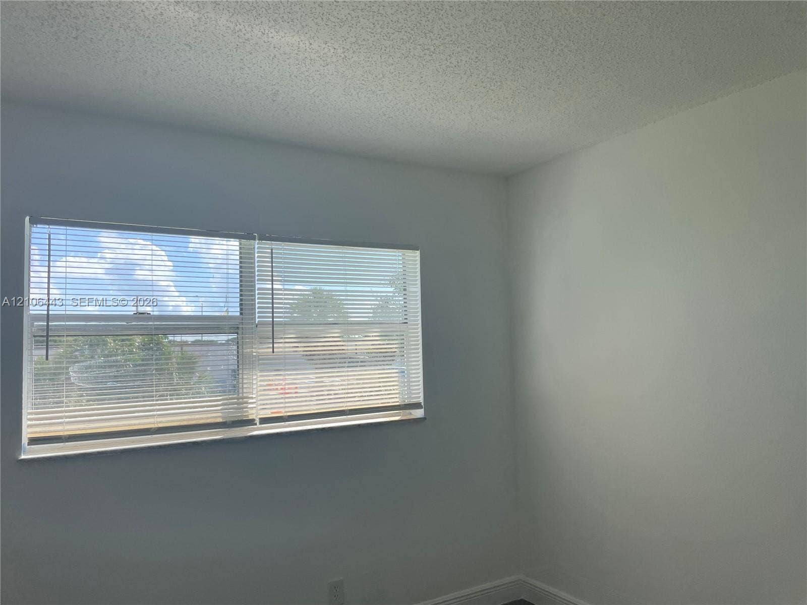 Interior space featuring neutral wall paint, textured ceiling, and a horizontal sliding window equipped with installed blinds