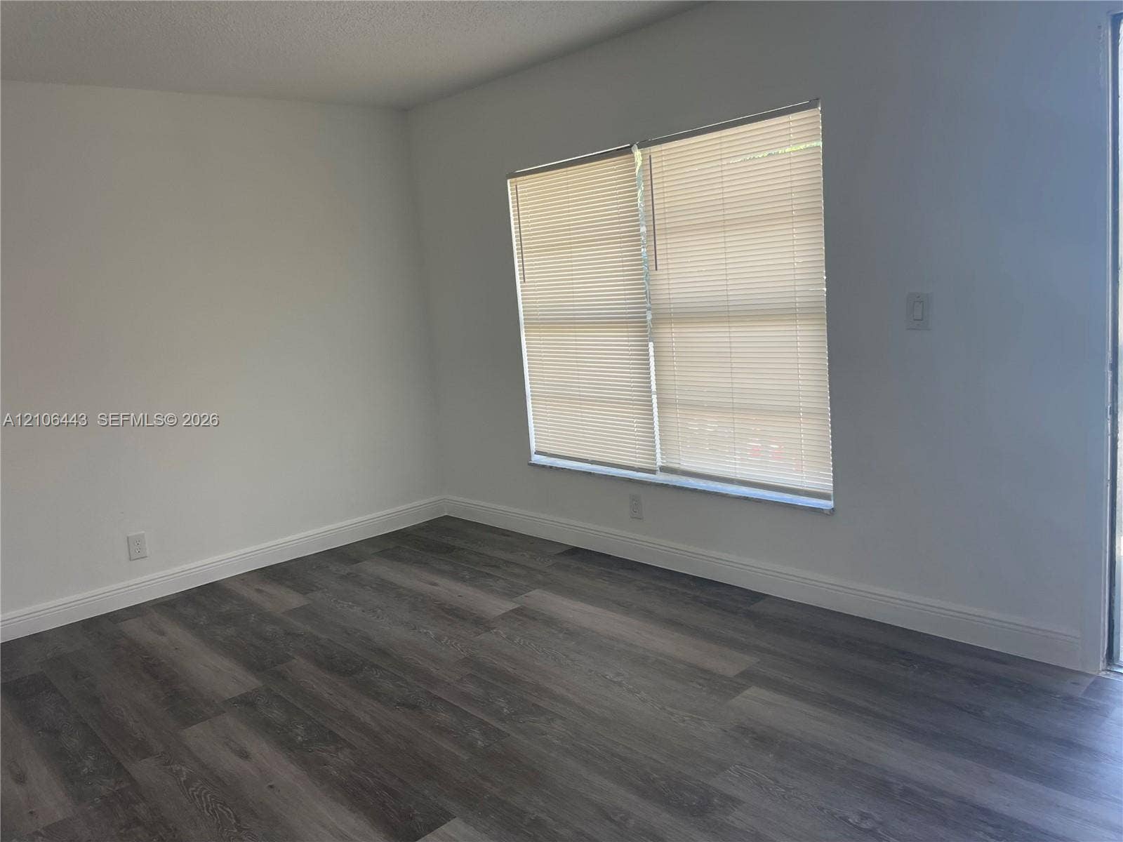 Room featuring wood-finish flooring, neutral walls, and dual windows with horizontal blinds