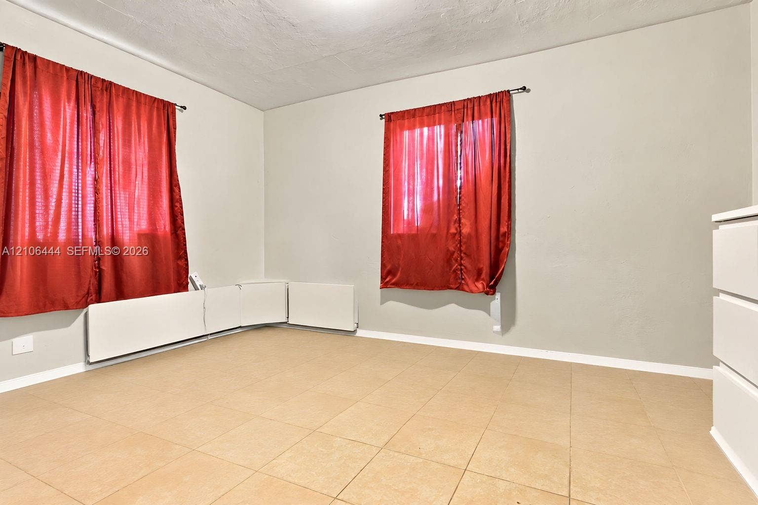 Neutral wall tones, ceramic tile flooring, and integrated wall-mounted heating units