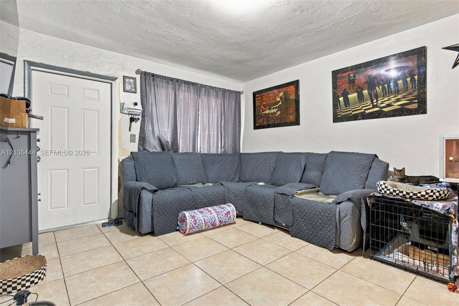 Neutral-toned ceramic tile flooring, solid-core four-panel entry door, and textured wall finish