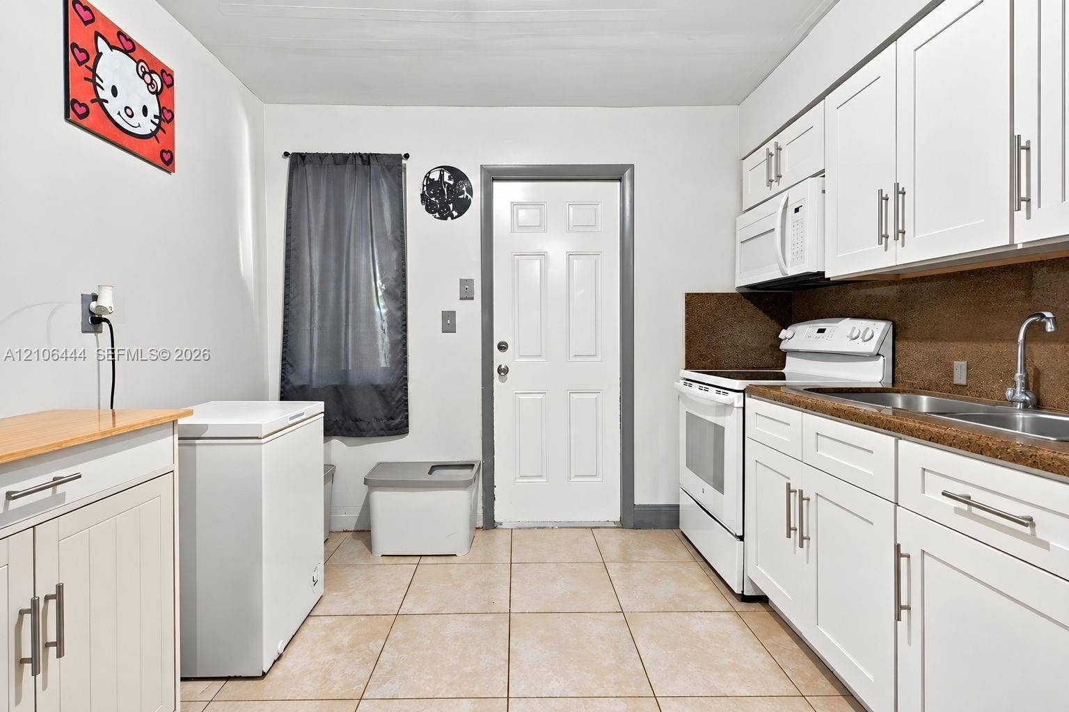 Kitchen featuring white shaker-style cabinetry, solid-surface countertops, tile flooring, and a stainless steel dual-basin sink