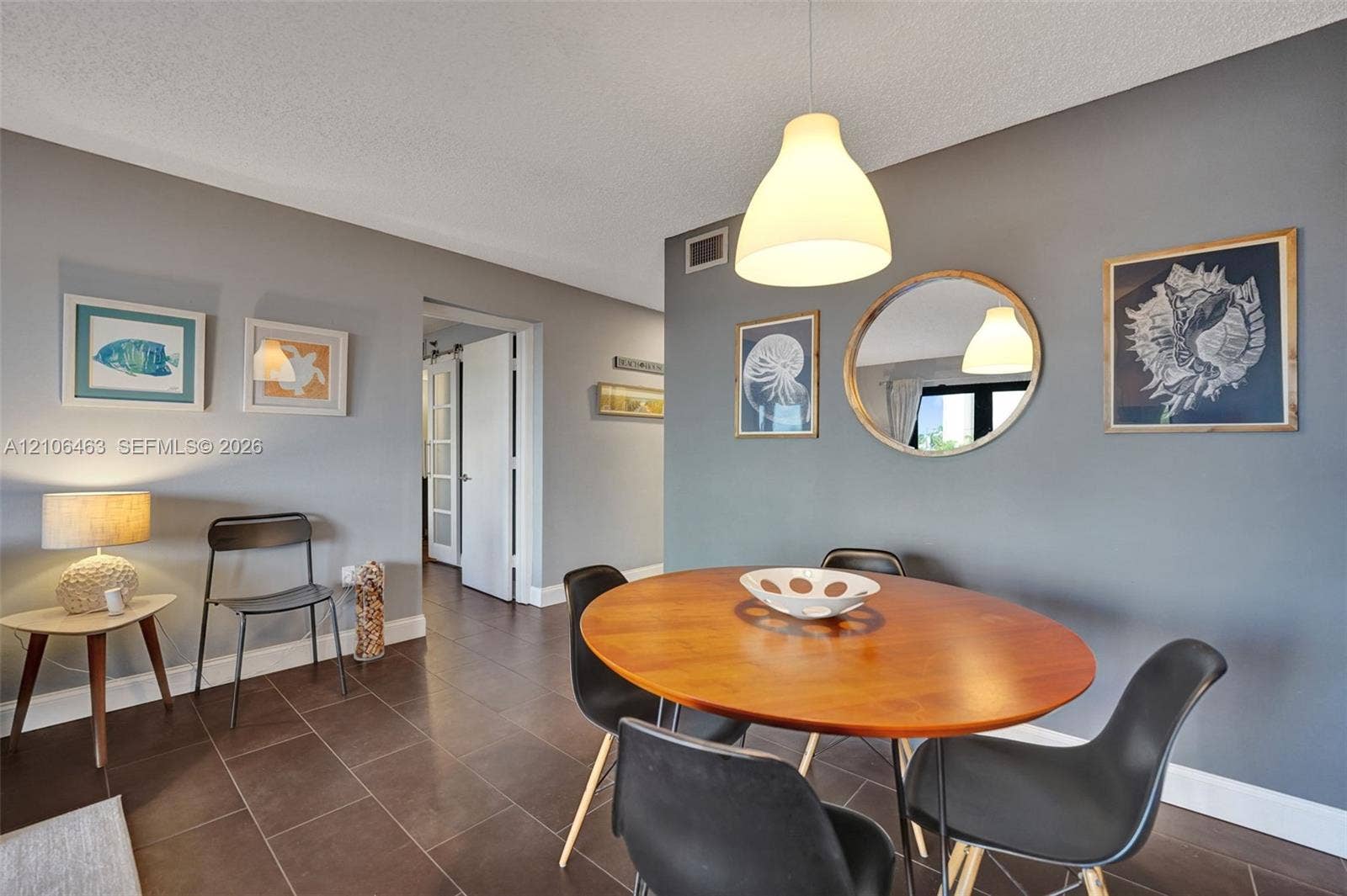 1201 S Ocean Drive, #218N, Hollywood, FL 33019 Neutral-toned walls featuring a recessed-mount round mirror, complemented by dark ceramic tile flooring and a minimalist dome-style pendant lighting fixture