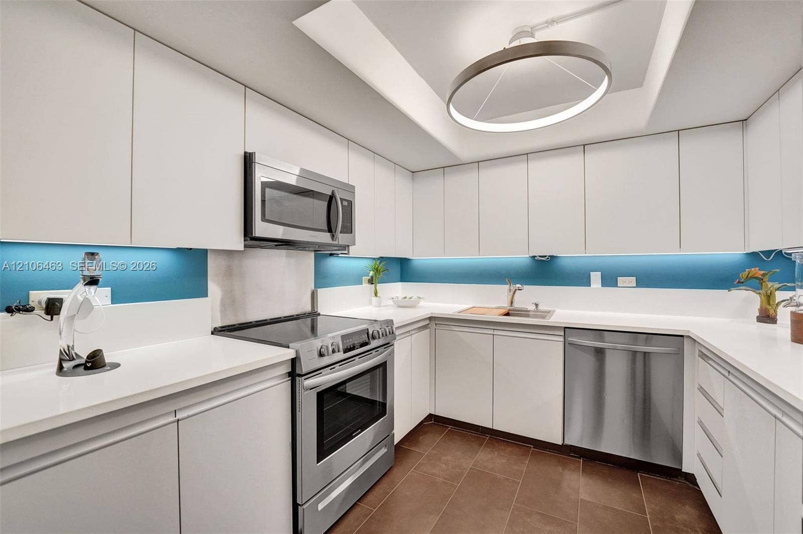 1201 S Ocean Drive, #218N, Hollywood, FL 33019 Kitchen featuring white flat-panel cabinetry, solid-surface countertops, stainless steel appliances, tiled flooring, and a recessed ceiling fixture with LED accent lighting