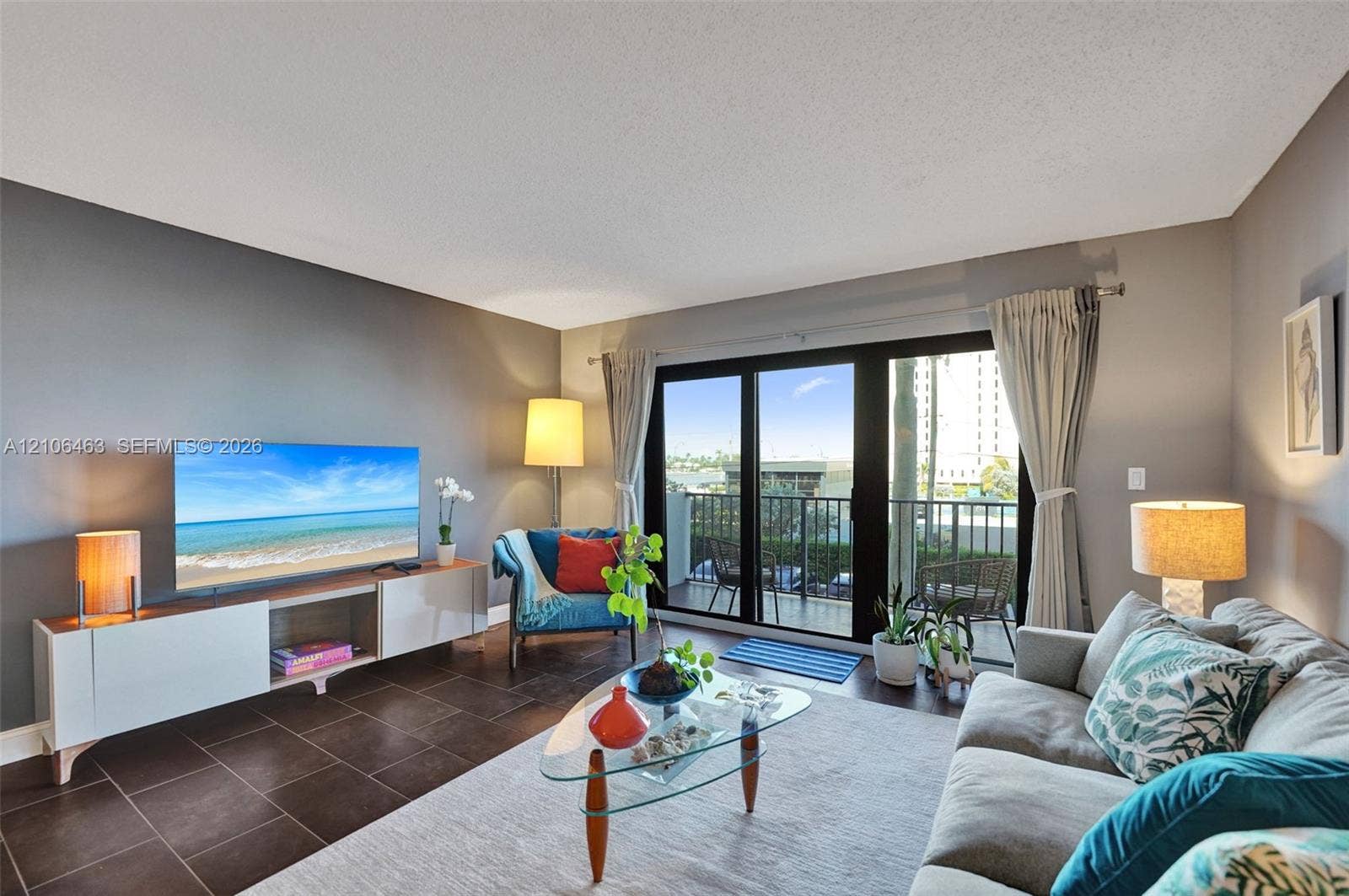 1201 S Ocean Drive, #218N, Hollywood, FL 33019 Living area featuring large format tile flooring, a dark-toned accent wall, and sliding glass doors with metal framing opening to a balcony
