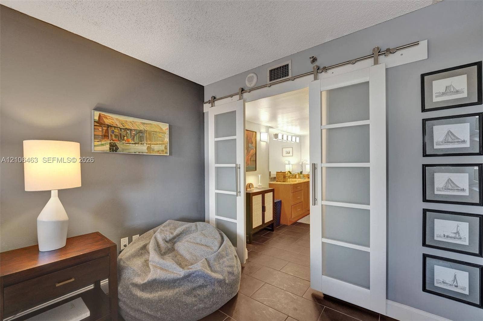 1201 S Ocean Drive, #218N, Hollywood, FL 33019 Double sliding doors with frosted glass panels and brushed-metal hardware, featuring a wood-tone vanity with integrated cabinetry and large-format tile flooring