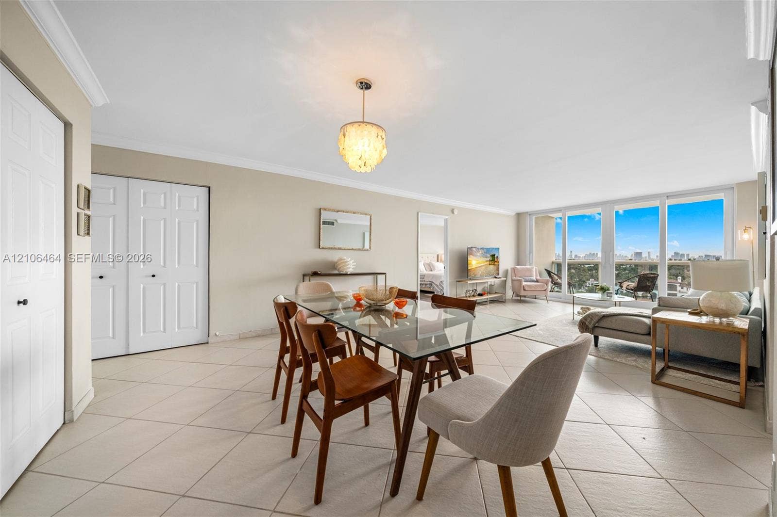 6770 Indian Creek Drive, #8E, Miami Beach, FL 33141 Open-concept living space featuring large-format ceramic tile flooring, floor-to-ceiling windows, and decorative drum-style chandelier lighting