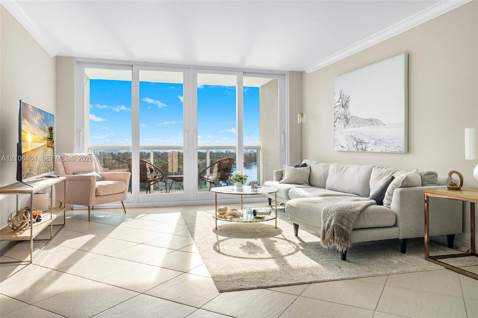 6770 Indian Creek Drive, #8E, Miami Beach, FL 33141 Living area featuring large-format diagonal tile flooring, crown molding, and floor-to-ceiling sliding glass doors opening to a balcony