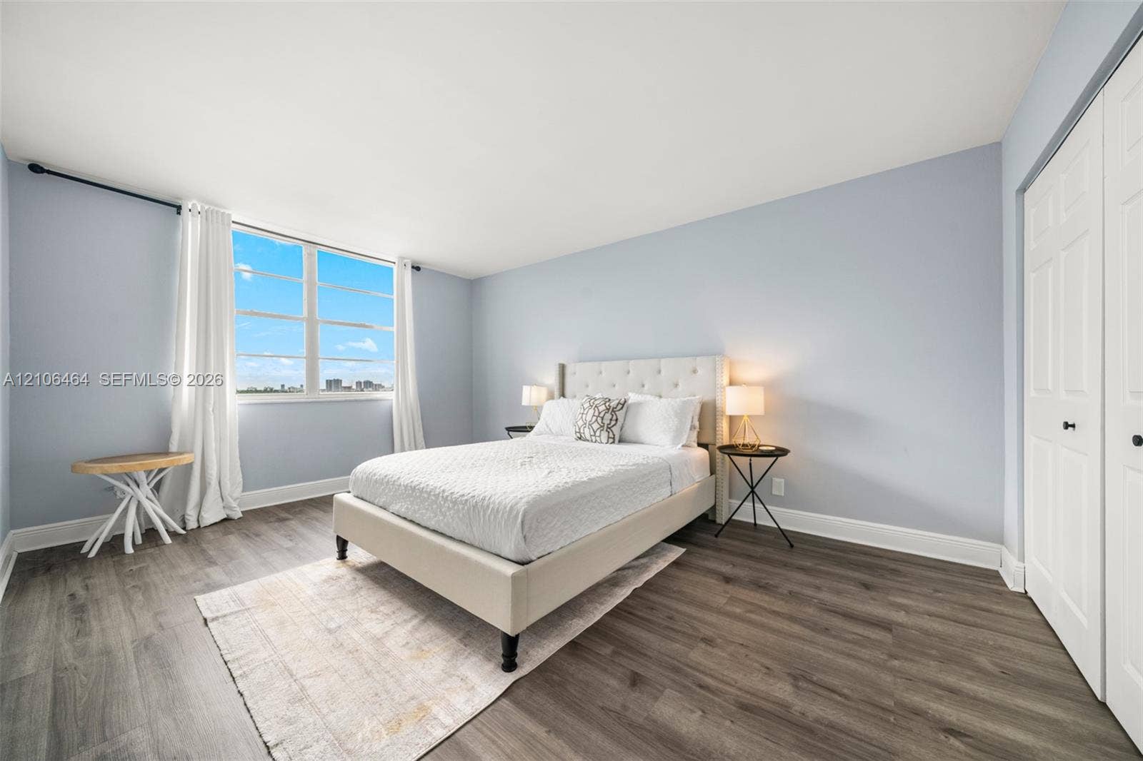 Bedroom featuring wood-finish flooring, large window, and double-door closet