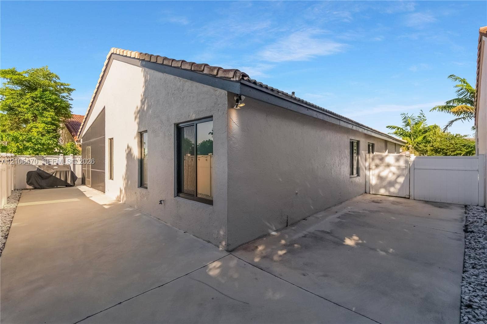 Stucco exterior featuring a concrete side yard, tile roof, and enclosed privacy fencing