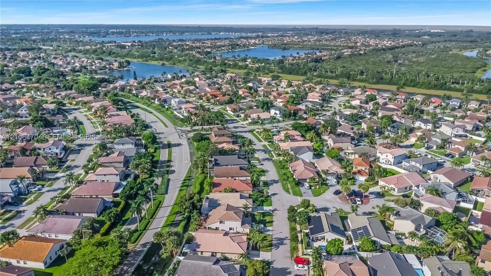 Aerial view of a residential neighborhood featuring paved roadways, diverse single-family homes, mature landscaping, and proximity to regional waterways