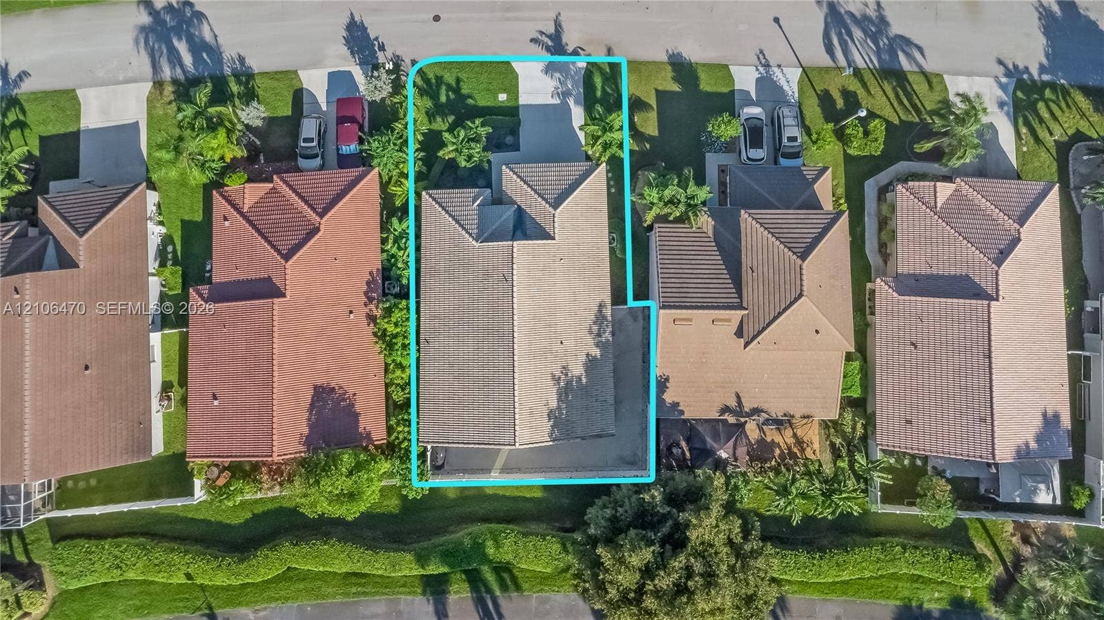 Aerial perspective of a residential lot featuring a concrete driveway, a tile roof, and a fenced rear perimeter