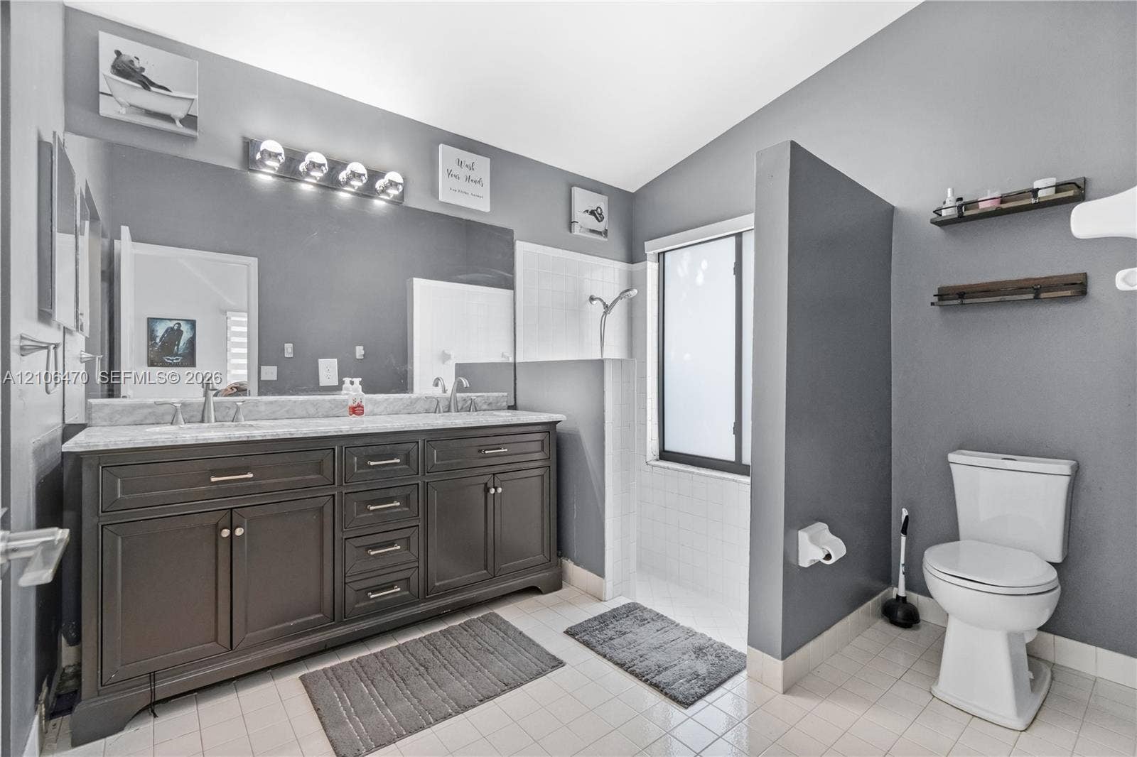 Double vanity featuring dark cabinetry, stone-finish countertops, dual under-mount sinks, and a full-width mirror