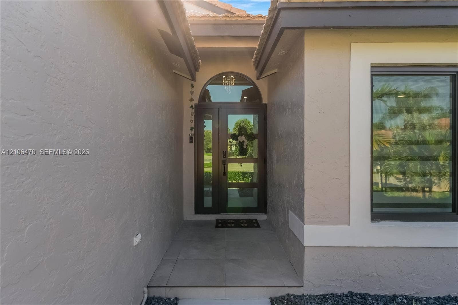 Entryway featuring a glass-panel door, arched transom window, recessed ceiling lighting, and large-format tile flooring