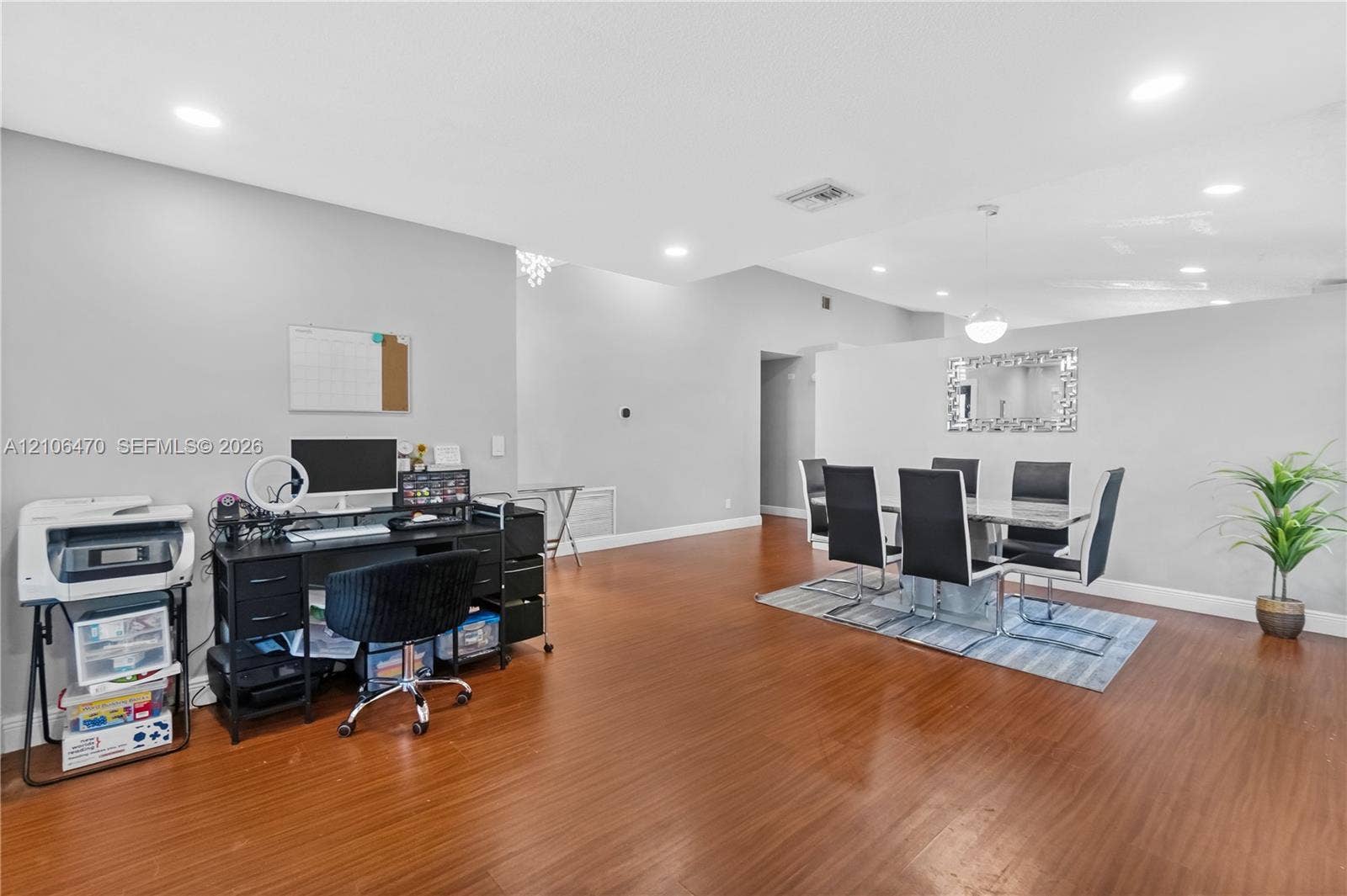 Open-concept floor plan featuring wood-finish flooring, recessed lighting, and a wall-mounted decorative mirror