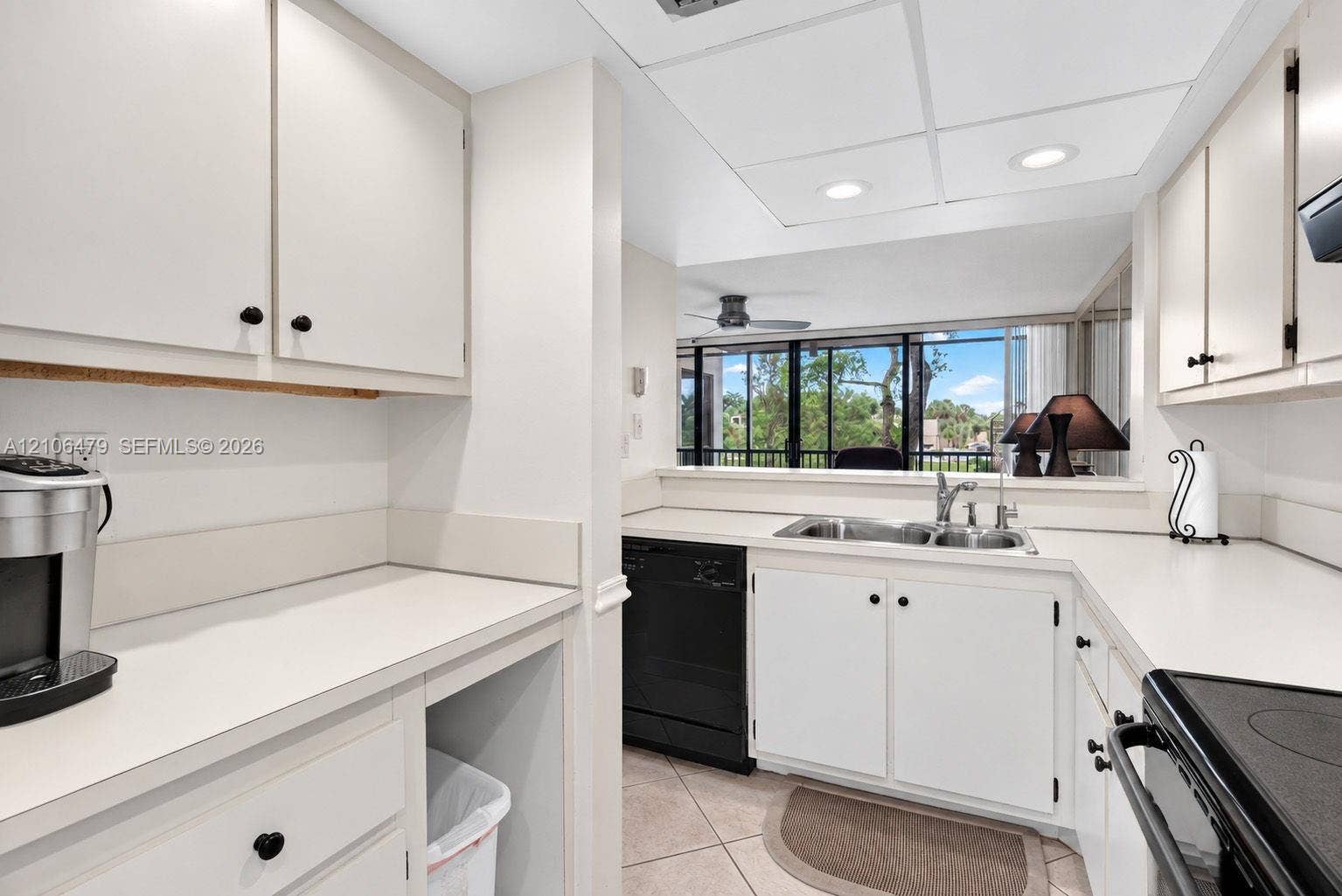 2800 SW 87th Avenue, #1113, Davie, FL 33328 Kitchen featuring solid-surface countertops, white cabinetry, a dual-basin stainless steel sink, recessed ceiling lighting, and ceramic tile flooring