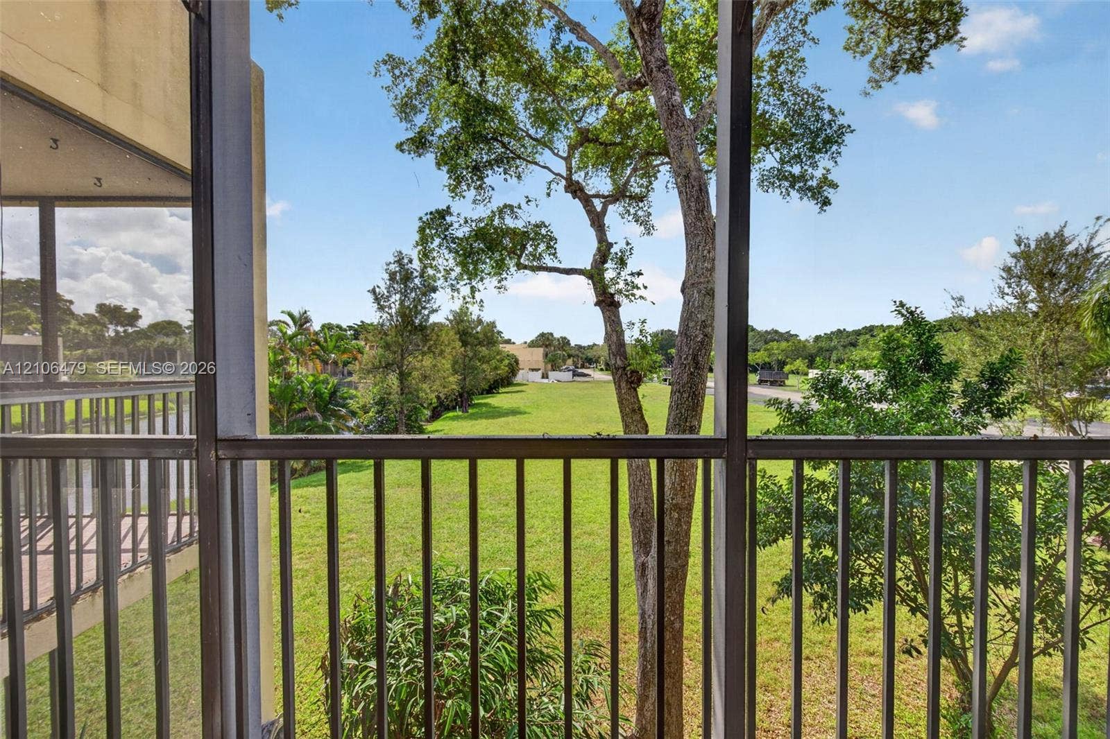 2800 SW 87th Avenue, #1113, Davie, FL 33328 Screened-in balcony featuring metal railings, overlooking an expansive lawn with mature trees