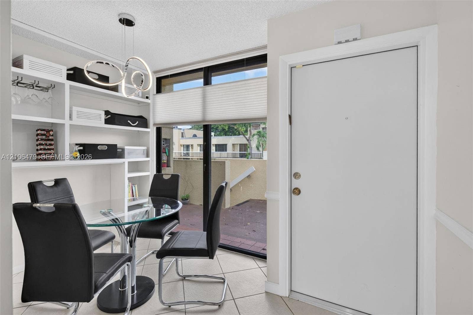 2800 SW 87th Avenue, #1113, Davie, FL 33328 Built-in white shelving, tile flooring, contemporary multi-ring pendant lighting, and large sliding glass door with external patio access