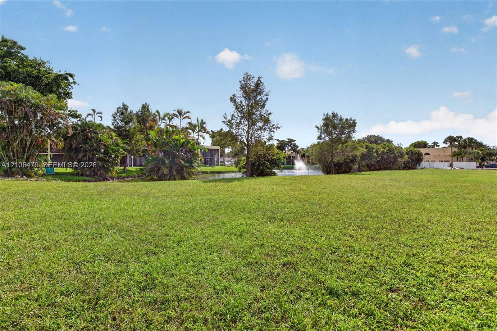 2800 SW 87th Avenue, #1113, Davie, FL 33328 Expansive green space featuring a manicured lawn, pond, water fountain, and mature tropical landscaping