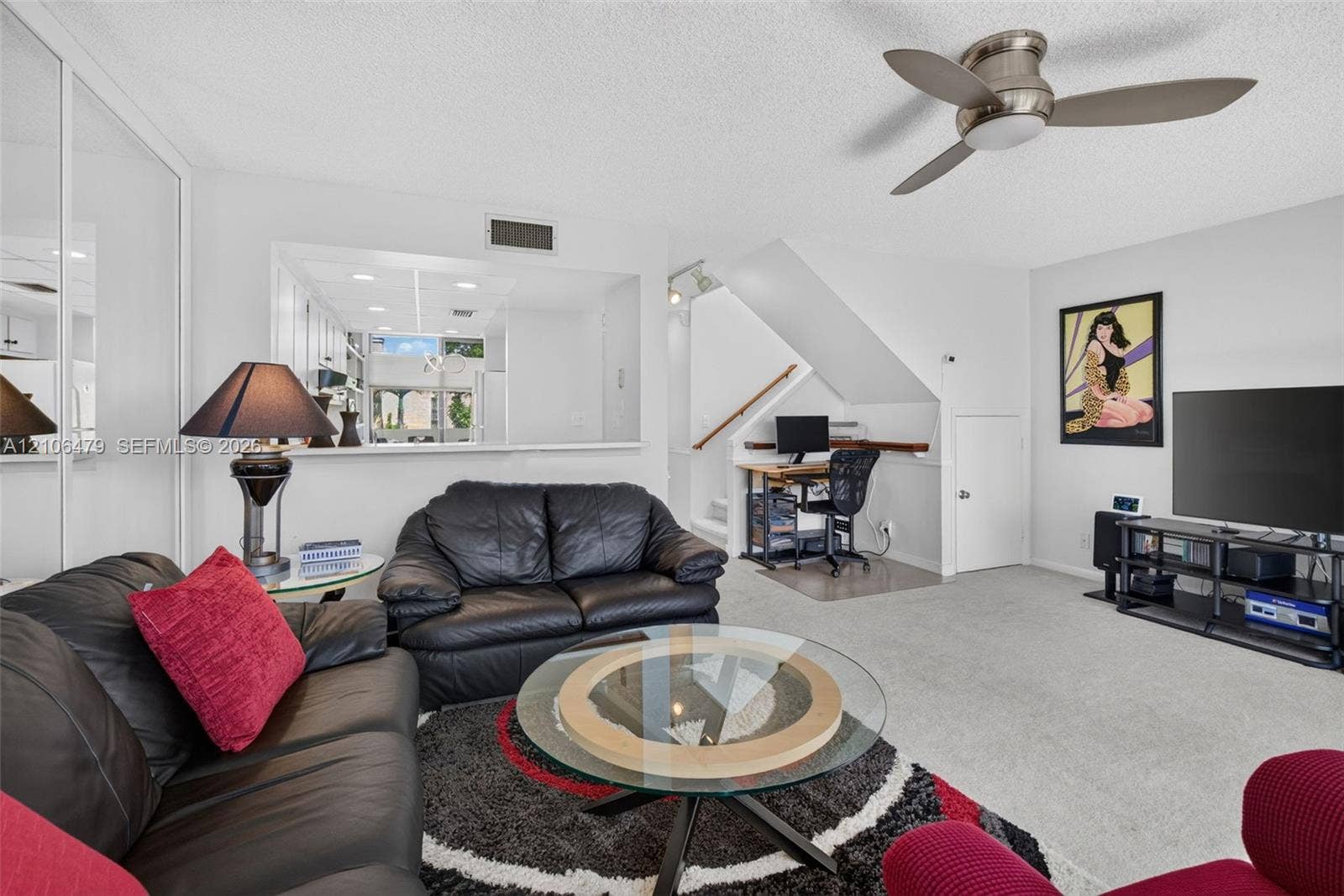2800 SW 87th Avenue, #1113, Davie, FL 33328 Living area featuring mirrored wall closet doors, a brushed-metal ceiling fan with integrated lighting, and an open pass-through window to the kitchen