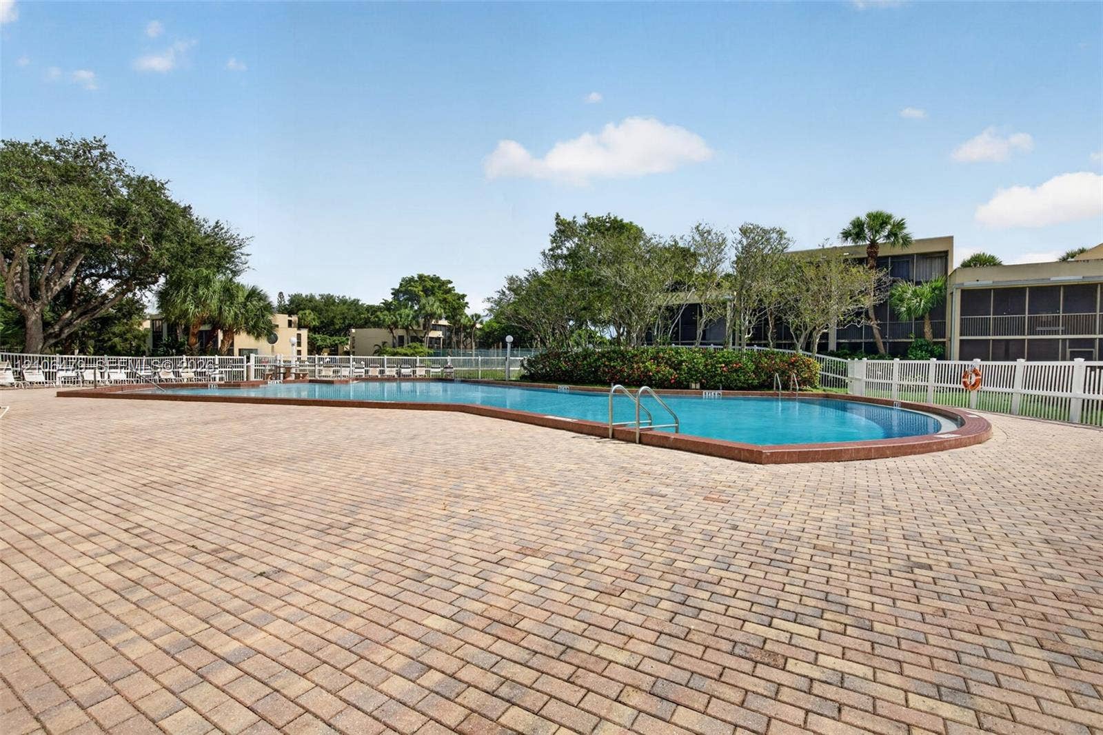 2800 SW 87th Avenue, #1113, Davie, FL 33328 In-ground swimming pool with a brick coping surround and expansive paver deck enclosed by white fencing