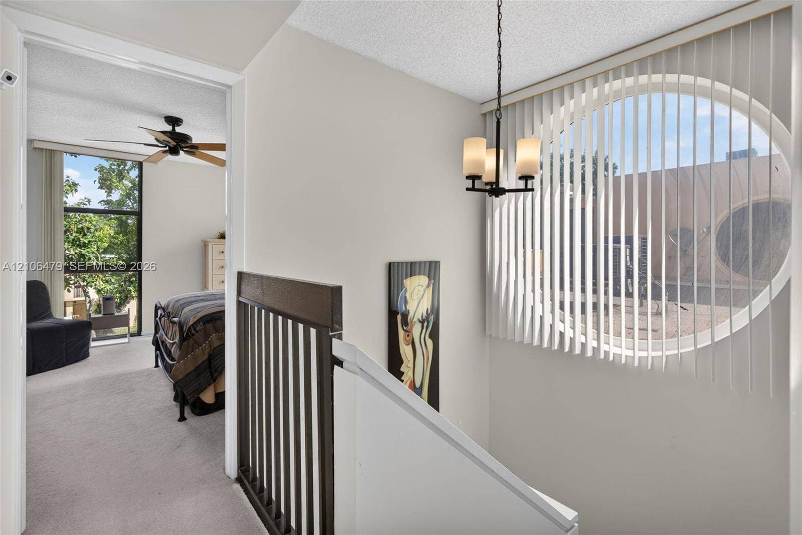 2800 SW 87th Avenue, #1113, Davie, FL 33328 Oval window with vertical blinds, three-light metal chandelier, and decorative wood-finish stair railing