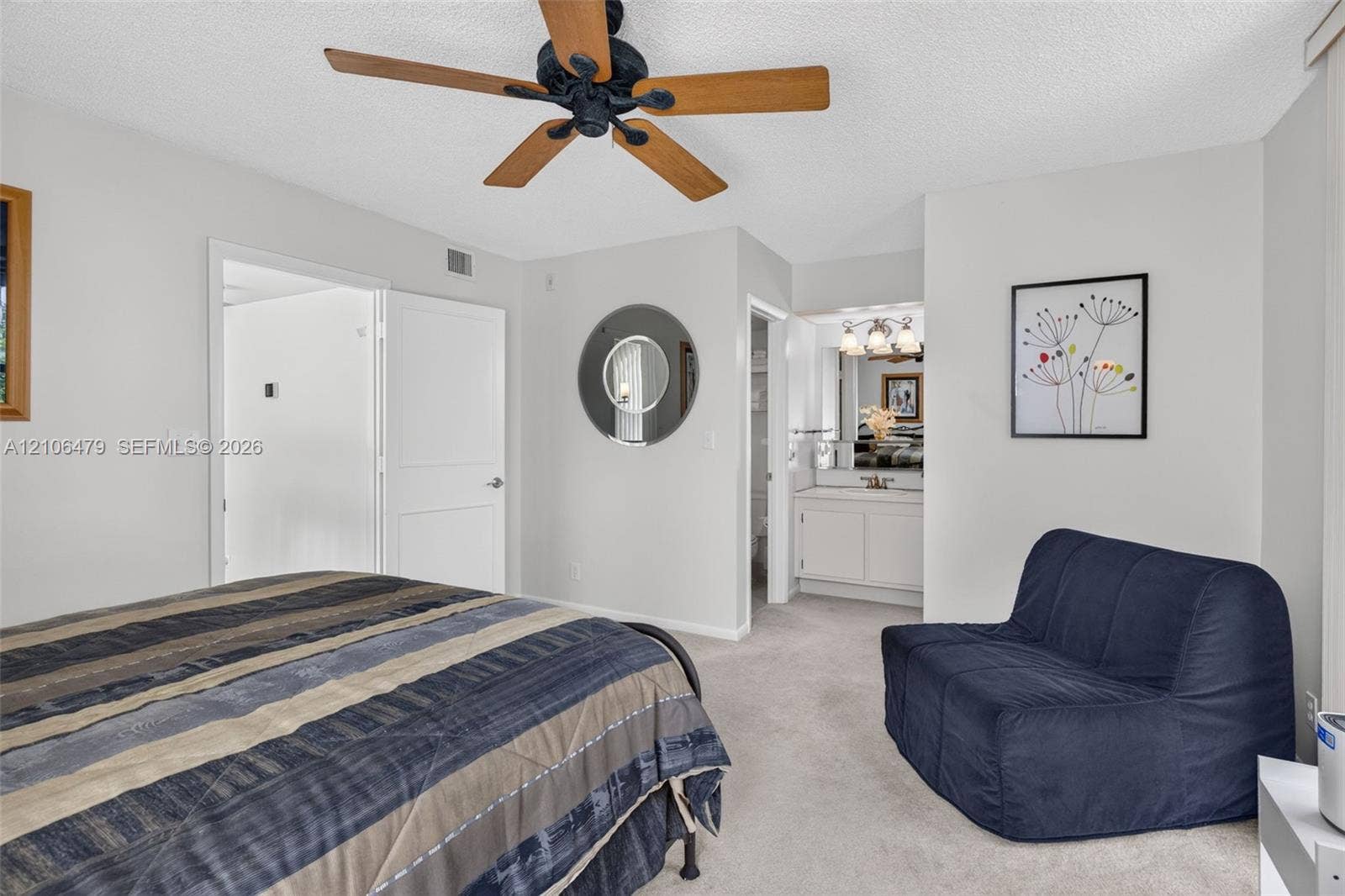 2800 SW 87th Avenue, #1113, Davie, FL 33328 Neutral interior space featuring carpeted flooring, a ceiling fan with wood-finish blades, a circular wall mirror, and a built-in vanity cabinet