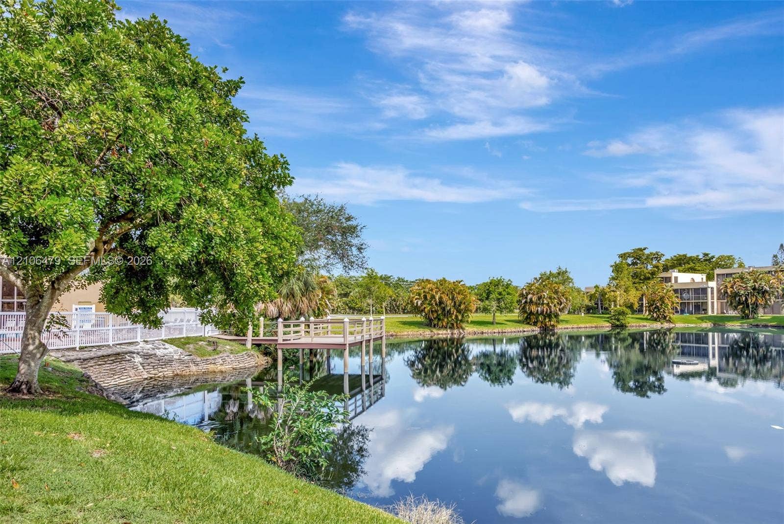 2800 SW 87th Avenue, #1113, Davie, FL 33328 Waterfront grounds featuring a private wooden dock, manicured lawn, mature trees, and stone-reinforced shoreline