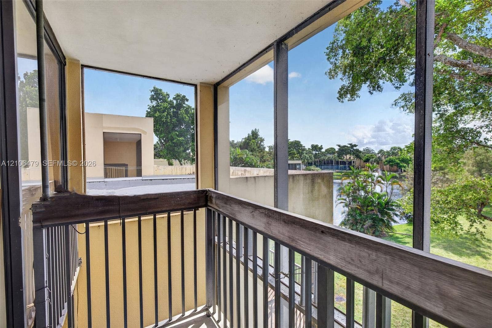 2800 SW 87th Avenue, #1113, Davie, FL 33328 Screened balcony featuring metal railings and wood-finish cap rails overlooking a pond and landscape