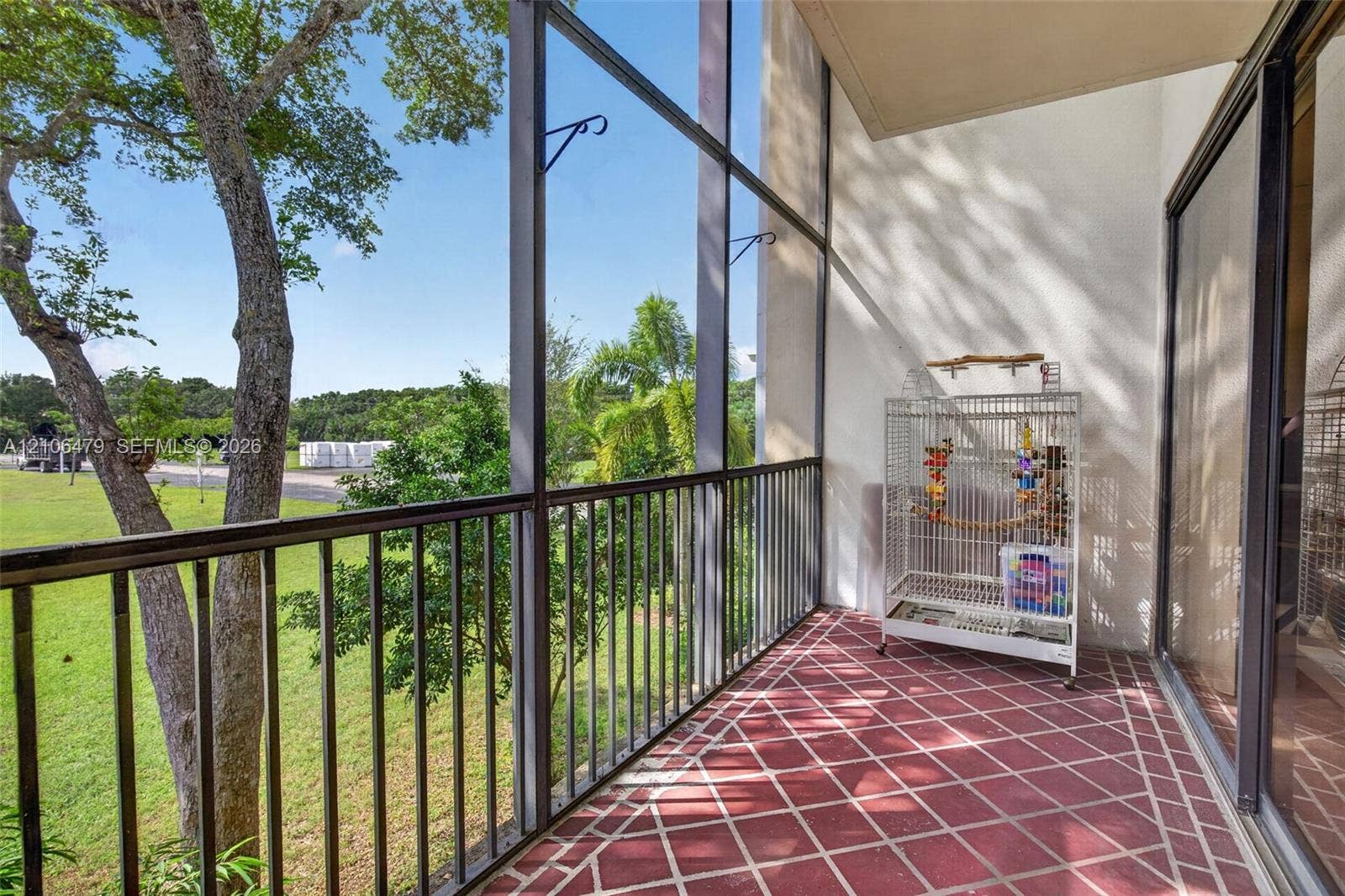 2800 SW 87th Avenue, #1113, Davie, FL 33328 Screened-in balcony featuring a red tiled floor, metal railings, and natural surroundings