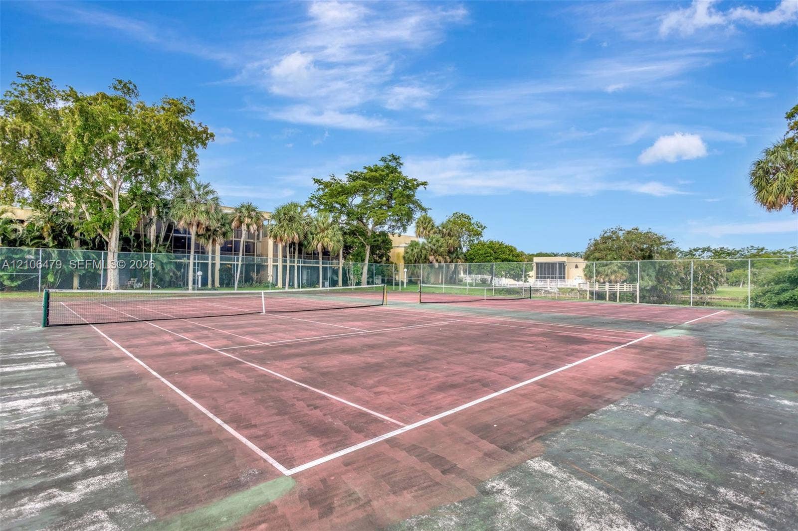 2800 SW 87th Avenue, #1113, Davie, FL 33328 Tennis court featuring a hard surface, perimeter chain-link fencing, and mature landscaping
